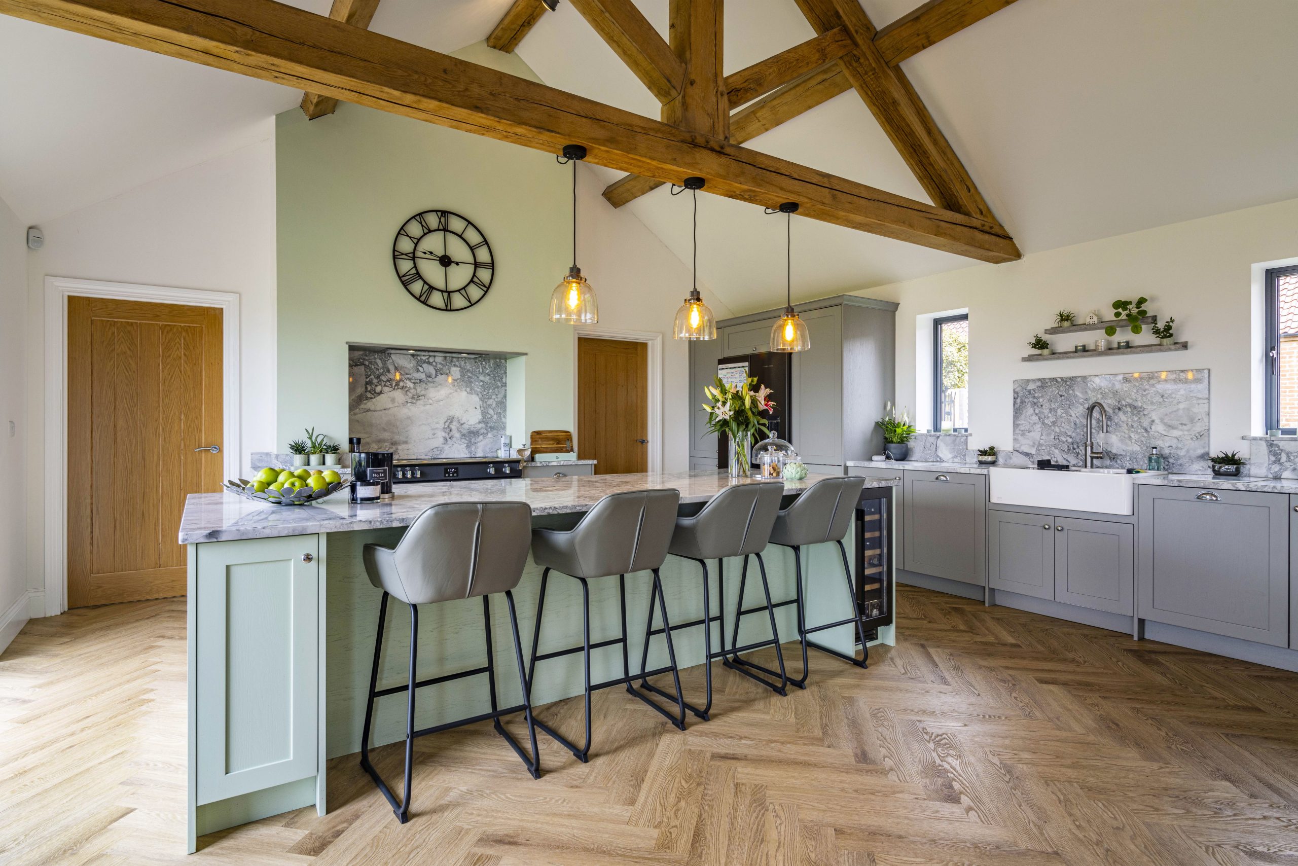 TheOldThreshingBarn-25 green shaker kitchen with island and bar stools. wooden beams in ceiling