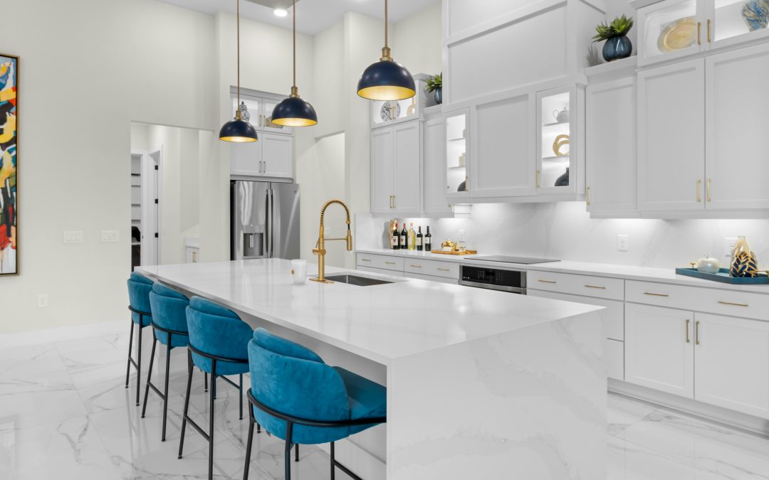 white kitchen with low hanging lighting and blue stool